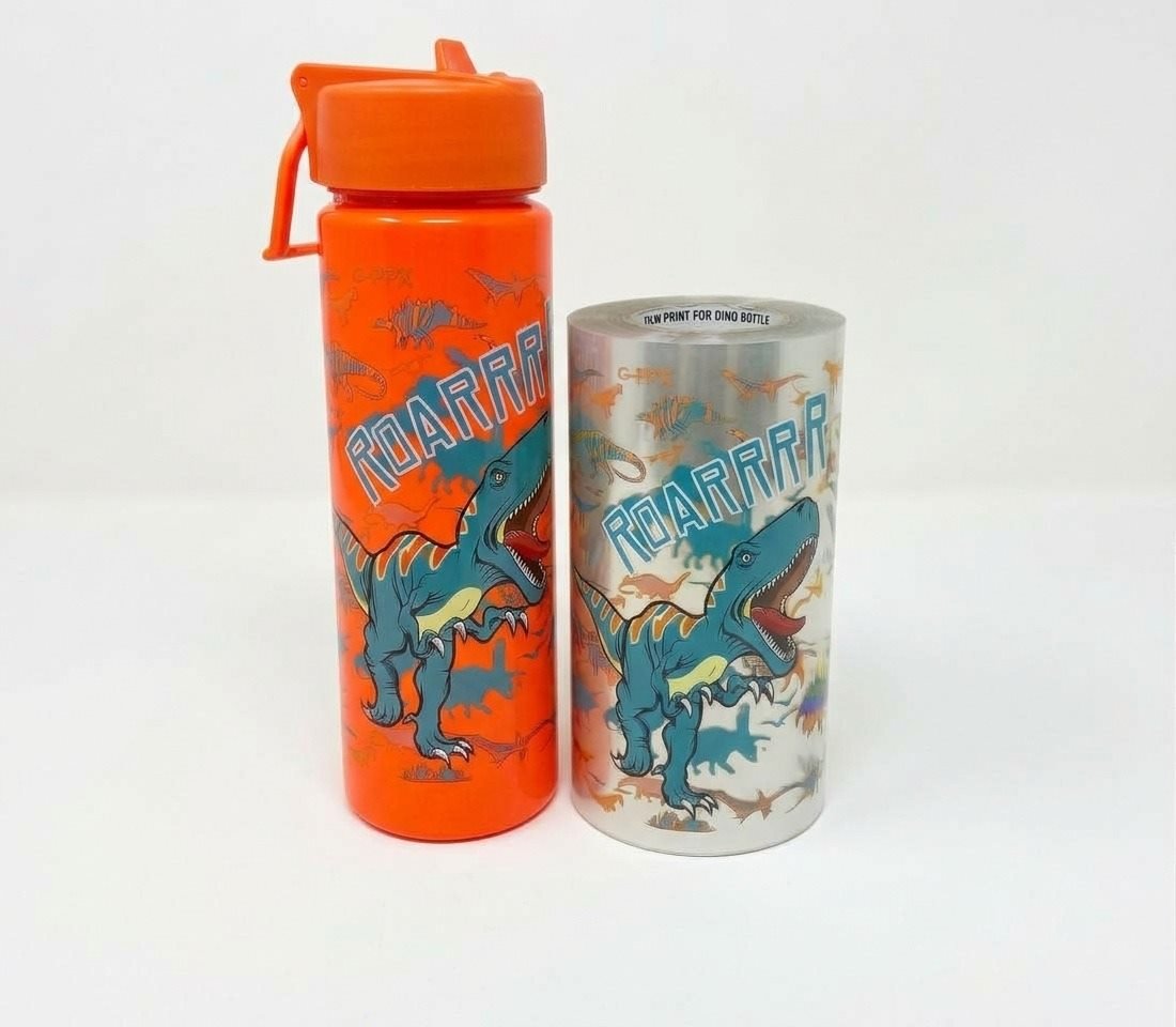 Botella decorada con Heat Transfer junto a rollo de película impresa